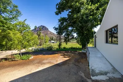 a house with a driveway with a mountain in the background at Florie se Huis in Paarl