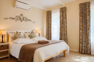 a bedroom with a bed with white sheets and a window at Skilpadvlei Wine Farm in Stellenbosch