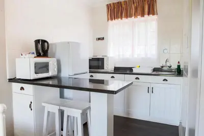 a kitchen with white cabinets and a counter with a microwave at Skilpadvlei Wine Farm in Stellenbosch