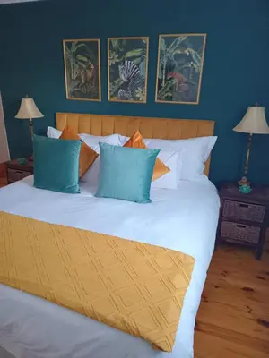 a bedroom with a large bed with blue and orange pillows at d'Vine Maison in Franschhoek
