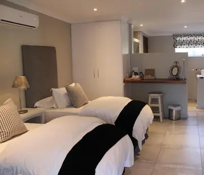 a bedroom with two beds and a kitchen at Nuwerus Lodge Paarl in Paarl