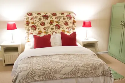 a bedroom with a bed with red pillows and two lamps at Nuwerus Lodge Paarl in Paarl