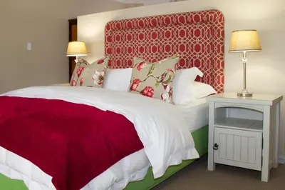 a bedroom with a large bed with a red headboard at Nuwerus Lodge Paarl in Paarl