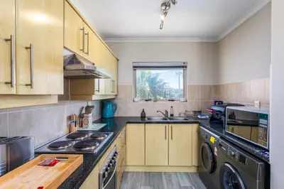 a kitchen with wooden cabinets and a washer and dryer at Dorphene 304 by CTHA in Cape Town
