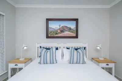 a bedroom with a white bed with two nightstands and two lamps at Island view on Clam in Cape Town