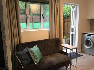 a living room with a couch and a window at Lovely studio apartment in Pinelands, Cape Town in Cape Town