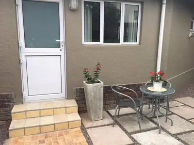 a patio with a table and chairs and a door at Lovely studio apartment in Pinelands, Cape Town in Cape Town