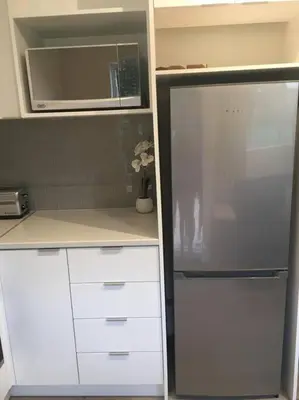 a kitchen with white cabinets and a microwave at Lovely studio apartment in Pinelands, Cape Town in Cape Town