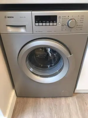 a silver washing machine sitting on a wooden floor at Lovely studio apartment in Pinelands, Cape Town in Cape Town