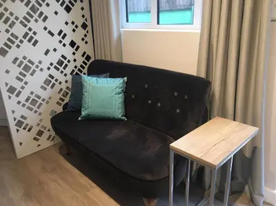 a black couch with a blue pillow next to a table at Lovely studio apartment in Pinelands, Cape Town in Cape Town