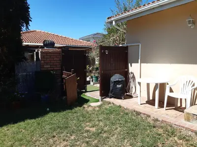 a backyard with a table and chairs and a fence at Cosy studio garden cottage in Cape Town