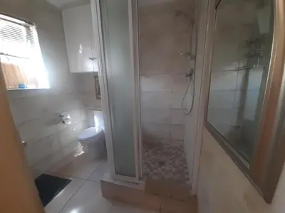 a bathroom with a shower and a toilet at Cosy studio garden cottage in Cape Town