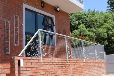 a house with a staircase with a wrought iron railing at At Hummingbird Hill Hermanus in Hermanus