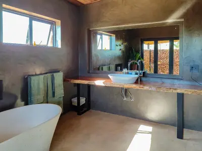 a bathroom with a tub and a sink and a mirror at Steenbok farm cottages Sunbird Cottage in Wolseley