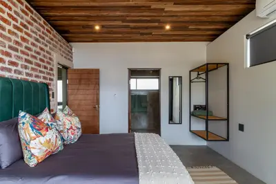 a bedroom with a bed and a brick wall at Steenbok farm cottages Kingfisher Cottage in Wolseley