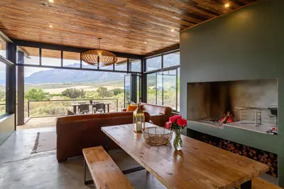 a living room with a table and a fireplace at Steenbok farm cottages Kingfisher Cottage in Wolseley