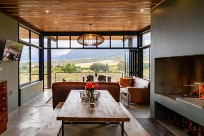 a living room with a table and a fireplace at Steenbok farm cottages Kingfisher Cottage in Wolseley
