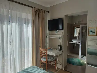 a bedroom with a bed and a desk and a television at Strandloper Room in Cape Town