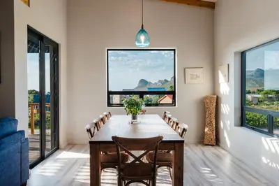 a dining room with a wooden table and chairs at Prinia on Peak holiday home in Pringle Bay