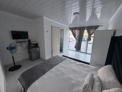 a white bedroom with a bed and a window at No 1 Guest house in Cape Town