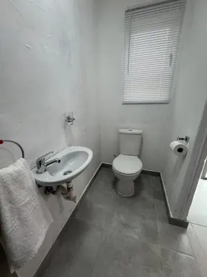 a white bathroom with a toilet and a sink at No 1 Guest house in Cape Town