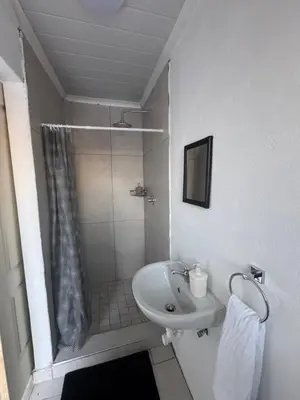 a white bathroom with a shower and a sink at No 1 Guest house in Cape Town
