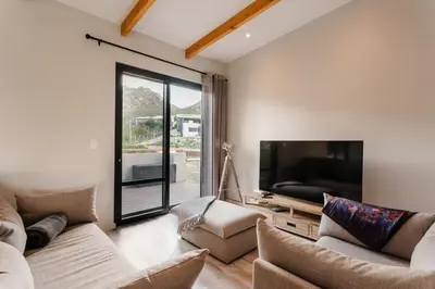 a living room with two couches and a flat screen tv at Prinia on Peak in Pringle Bay in Pringle Bay