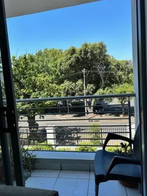 a balcony with a chair and a view of a parking lot at Cozy Rondebosch Apartment in Cape Town