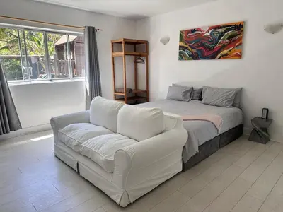 a living room with a bed and a couch at Sunset Studio Garden View in Cape Town