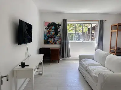 a living room with a white couch and a window at Sunset Studio Garden View in Cape Town