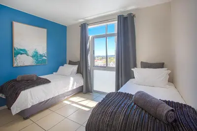 two beds in a room with a window at Isla's Place (Strandsig 304) in Cape Town