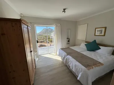 a bedroom with a large bed and a large window at Die Steenhuisie in Pringle Bay
