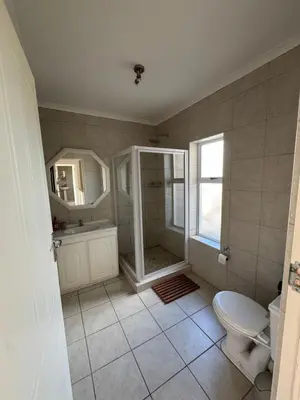 a bathroom with a shower and a toilet and a sink at Die Steenhuisie in Pringle Bay