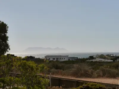 a house on the beach with the ocean in the background at Die Steenhuisie in Pringle Bay