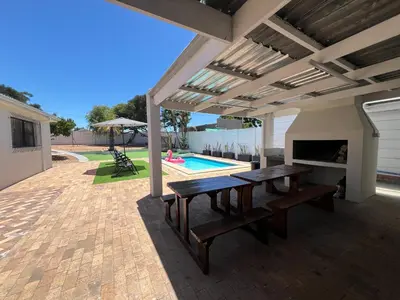 a patio with a table and a fireplace and a pool at Villa Lamsyh- your second home in Cape Town