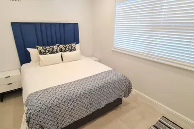 a bedroom with a bed with a blue headboard and a window at Villa Lamsyh- your second home in Cape Town