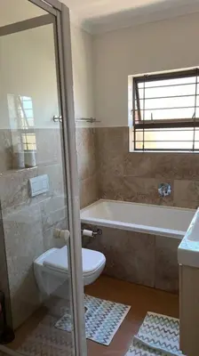 a bathroom with a toilet and a tub and a sink at Bosch Villa in Cape Town