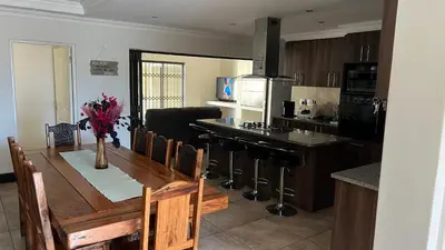 a kitchen and dining room with a wooden table and a counter at Bosch Villa in Cape Town