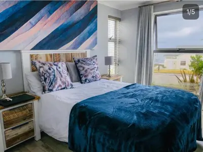 a bedroom with a large bed and a large window at Refresh at 50 Whale Rock in Hermanus