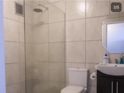 a bathroom with a shower with a toilet and a sink at Refresh at 50 Whale Rock in Hermanus
