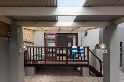 a patio with a wooden deck with a railing at 'Seagul Cove', Private Villa on the beach, Sleeps 7 in Cape Town