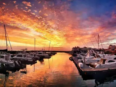 a group of boats docked in a marina at sunset at 'Seaside Cottage', Sleeps 4 with a 3 minute walk from the beach! in Cape Town
