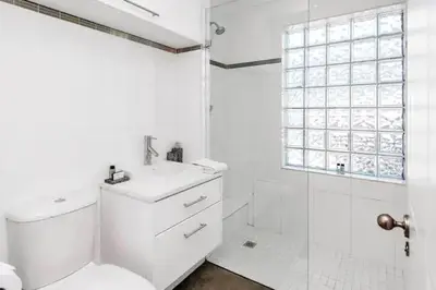 a white bathroom with a toilet and a shower at Cosy Home in Claremont in Cape Town