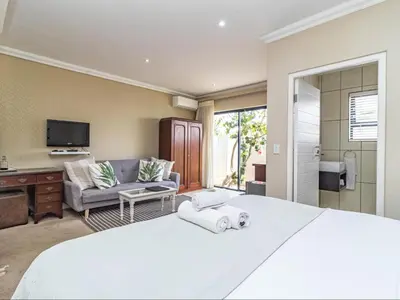 a bedroom with a large bed and a living room at Hermanus Cliff Path Lodge - No Load-shedding in Hermanus