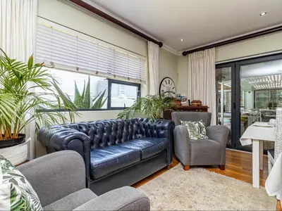 a living room with a leather couch and two chairs at Hermanus Cliff Path Lodge - No Load-shedding in Hermanus