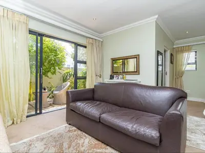 a leather couch in a living room with a large window at Hermanus Cliff Path Lodge - No Load-shedding in Hermanus