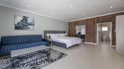 a bedroom with a bed and a blue couch at Inkantu Apartments & Suites in Cape Town