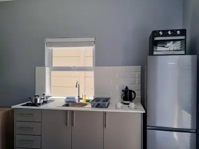 a kitchen with a sink and a refrigerator at Inkantu Apartments & Suites in Cape Town
