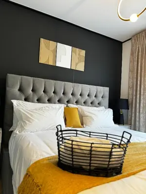 a bedroom with a large bed with white sheets and yellow pillows at S.A.E. Nine Palms Luxury in Cape Town