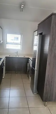 an empty kitchen with a sink and a refrigerator at The Sandown Blouberg self catering unit in Parklands